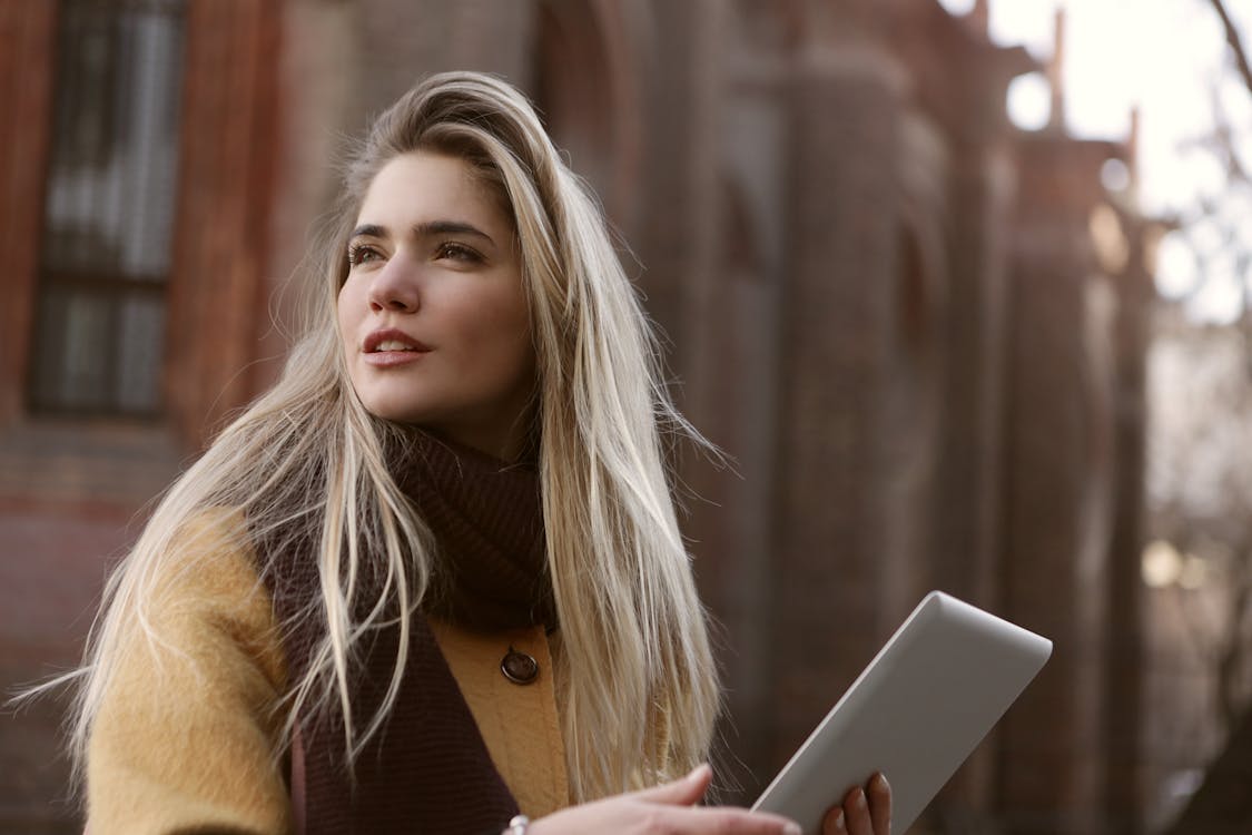 Woman in Brown Coat Holding Silver Ipad