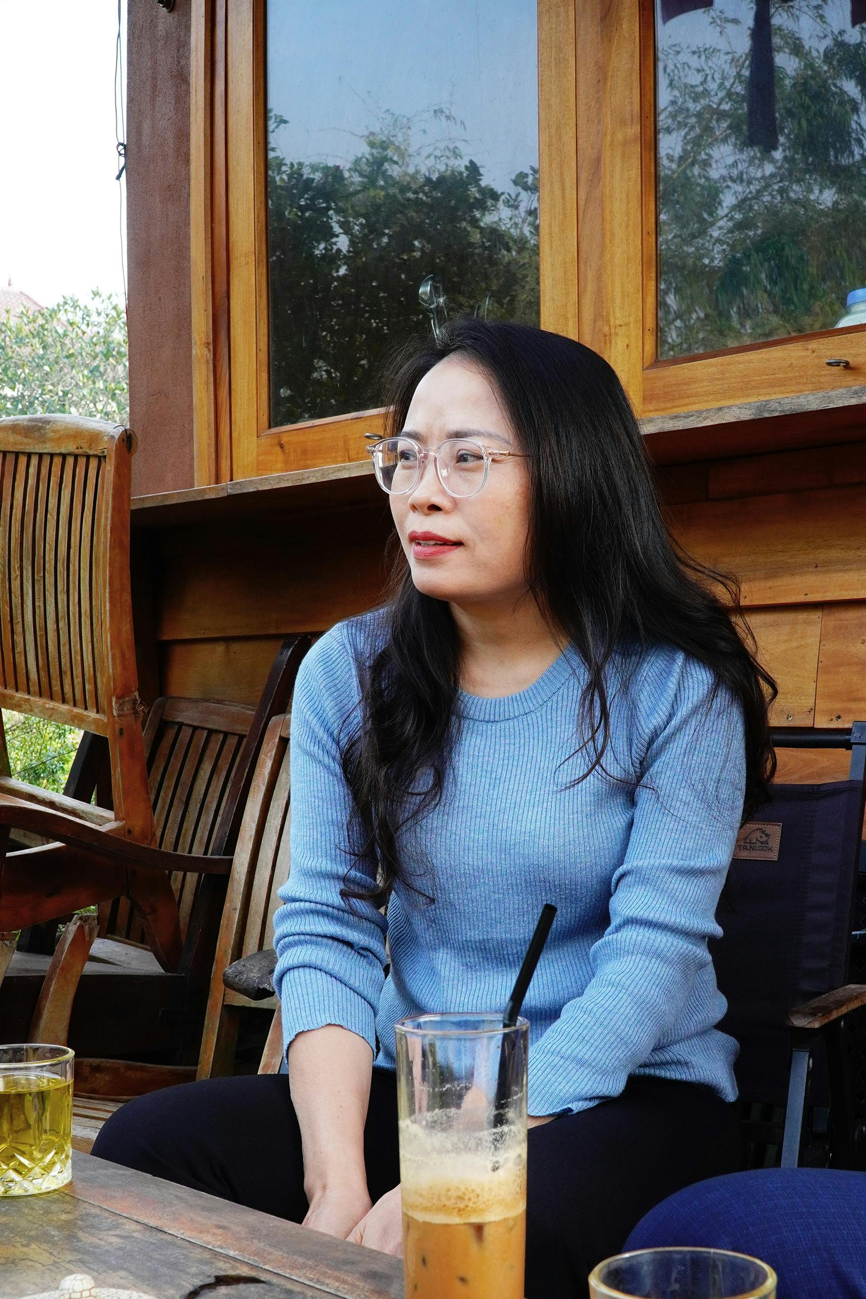 A woman enjoying drinks at a café in Vinh Phú, Việt Nam, in a relaxed outdoor setting.
