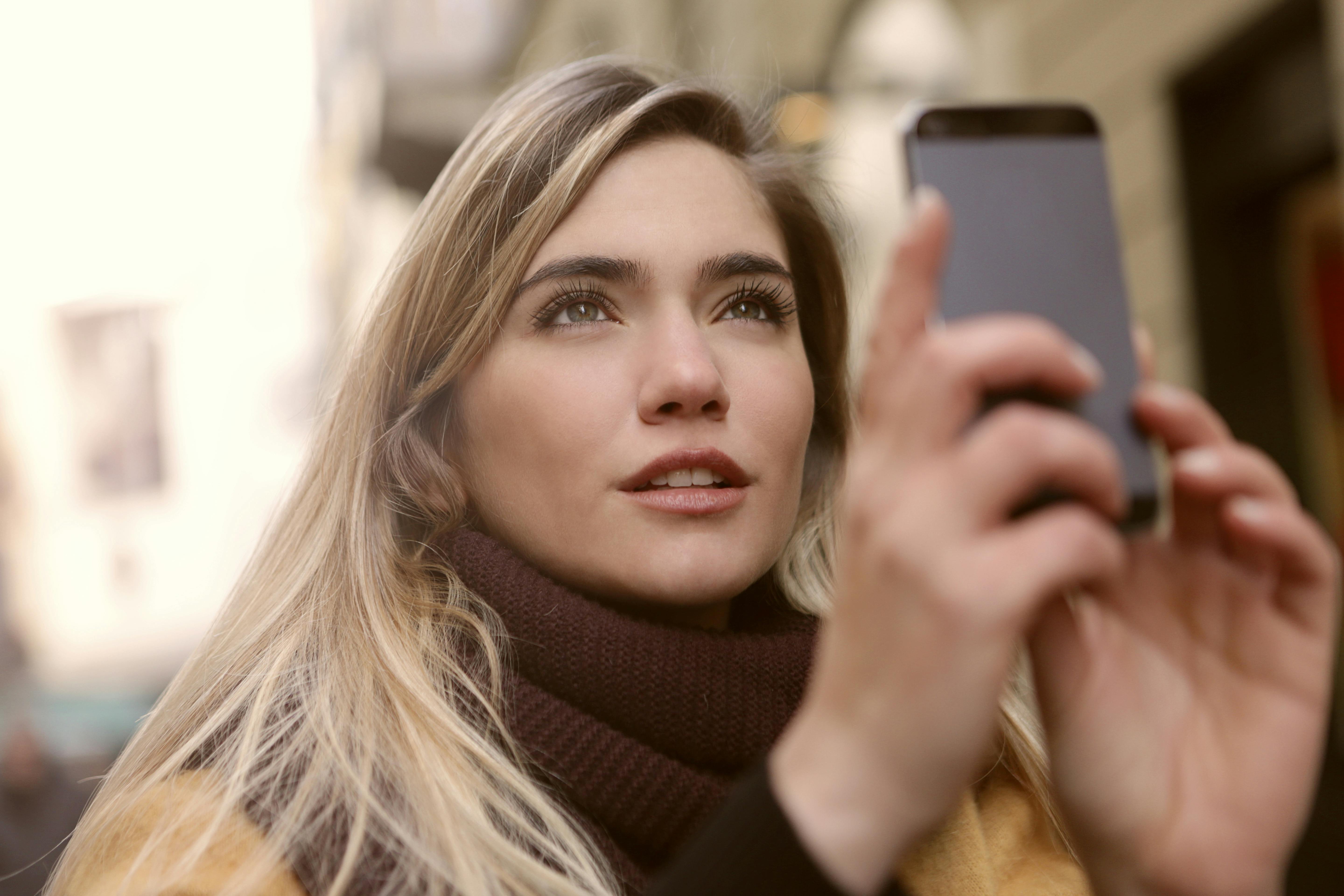 selective focus photo of woman holding a smartphone