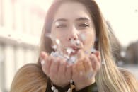 一位年轻女子在柔和的阳光下在户外吹五彩纸屑，营造出欢乐梦幻的氛围