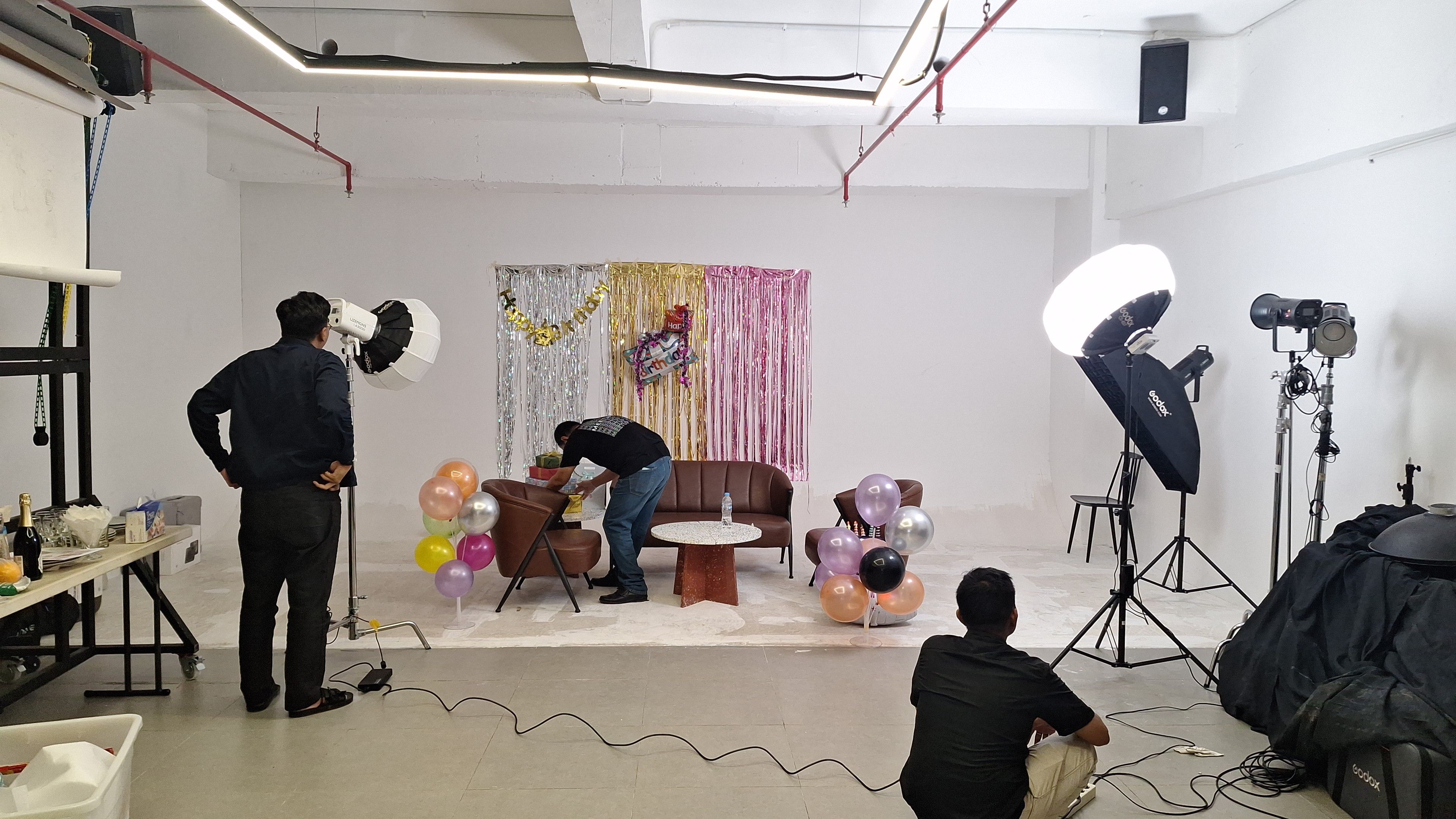 Photography studio setup with lighting equipment and colorful party decorations.