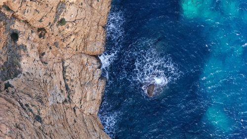 Free Stunning aerial shot of the rocky coastline in Spain with waves crashing against the cliffs and vibrant turquoise water. Stock Photo