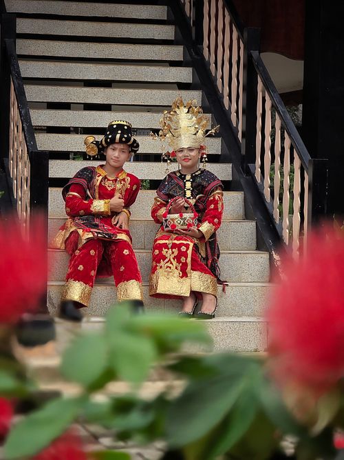 Free Two children in vibrant traditional costumes sit on steps, showcasing cultural heritage. Stock Photo