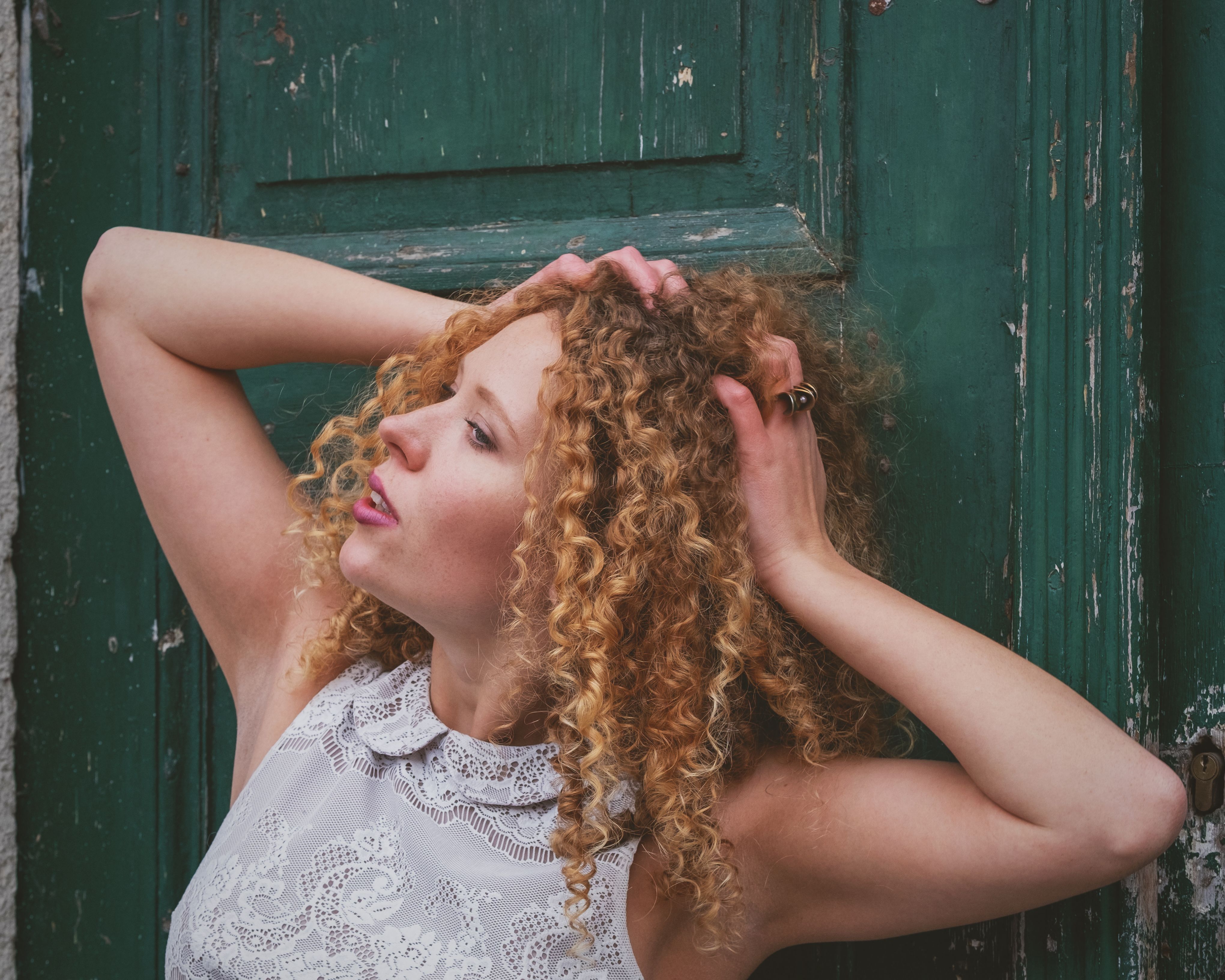 Captivating outdoor portrait of a woman with curly hair against a rustic green door backdrop.
