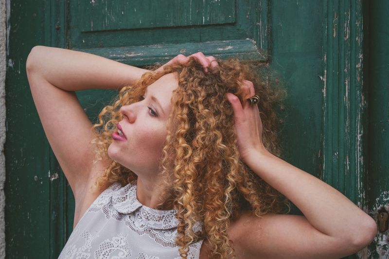 Captivating outdoor portrait of a woman with curly hair against a rustic green door backdrop.