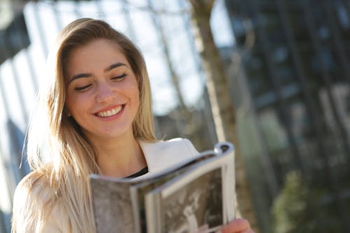 Woman in White Top While Holding Book