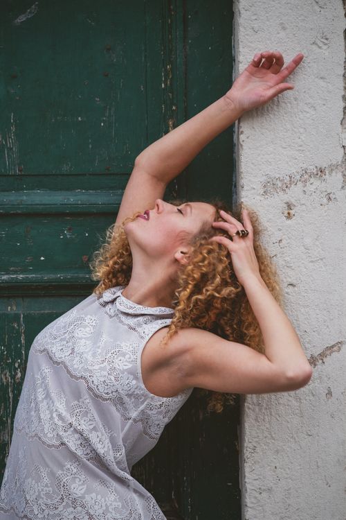 Free A woman in a lace dress expressing emotion against a weathered door. Stock Photo