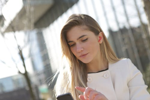 Frau Im Weißen Blazer, Der Schwarzes Smartphone Hält