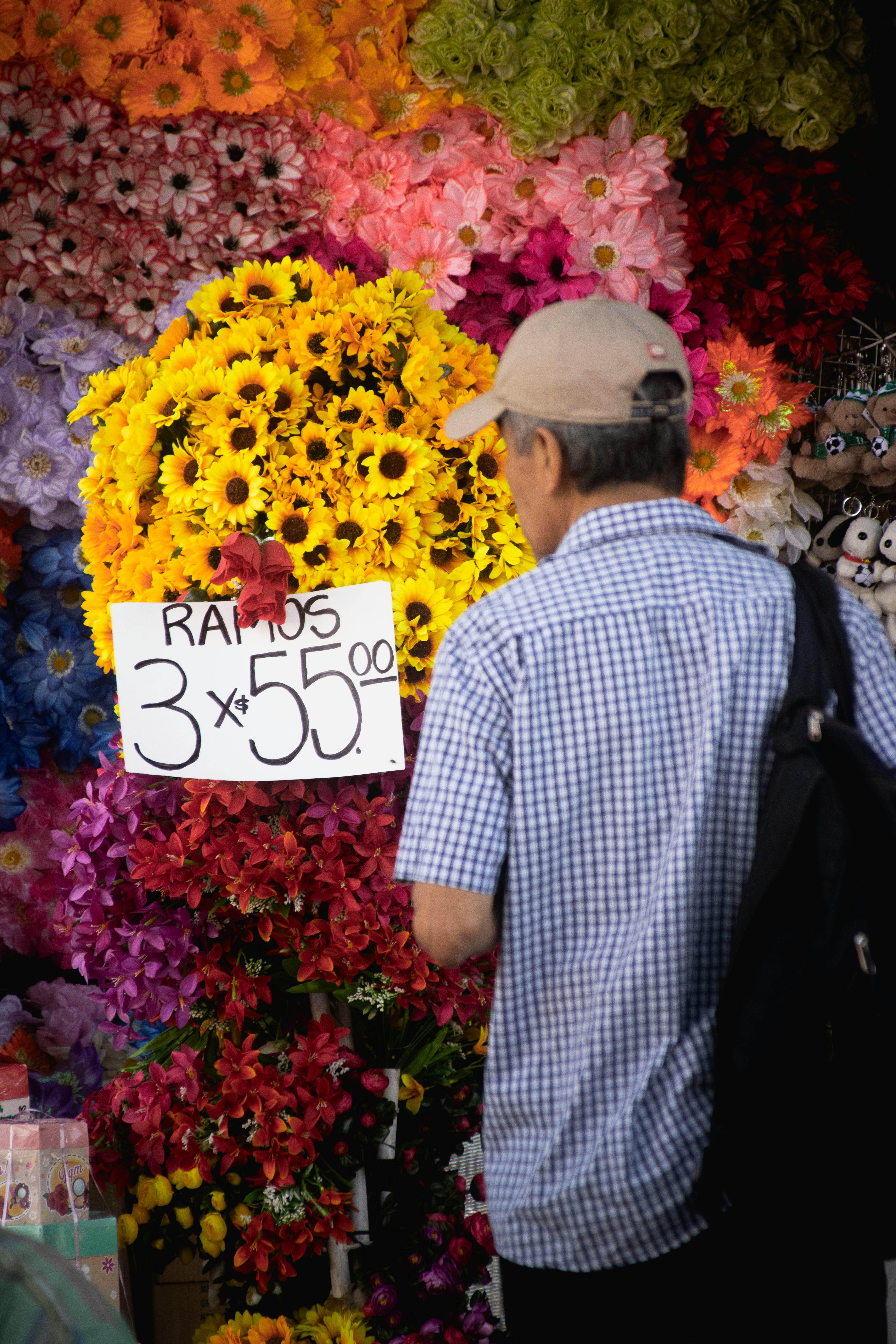 Vibrant display of flowers at a Mexico City market with a senior browsing the selection.