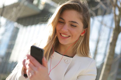 Glimlachende Vrouw In Witte Blazer Met Zwarte Smartphone