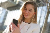 阳光明媚的日子里，一位年轻女子在户外享受着使用智能手机的时光
