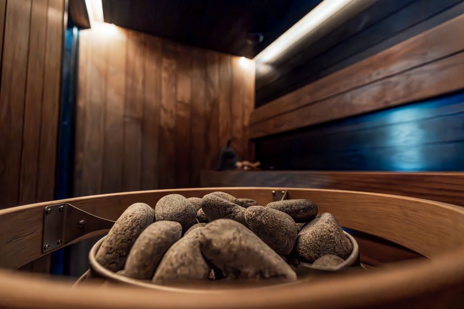 Elegant modern indoor sauna featuring dark wood and electric heater surrounded by stylish lighting.