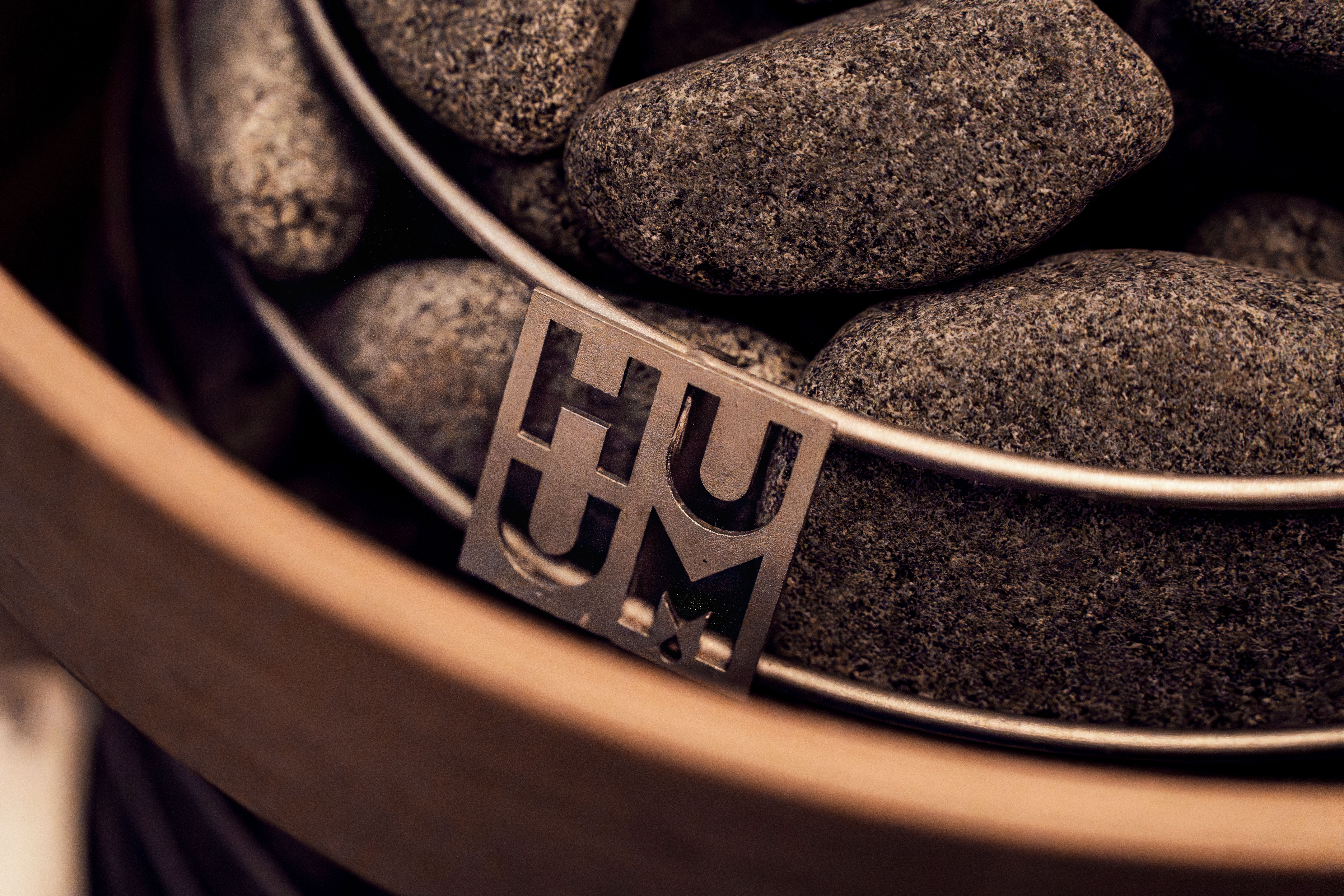 Stylish modern sauna heater with stones, featuring HUUM logo, ideal for spa or wellness settings.