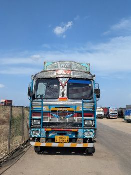 A vibrant Indian cargo truck parked on a rural road under a clear blue sky.
