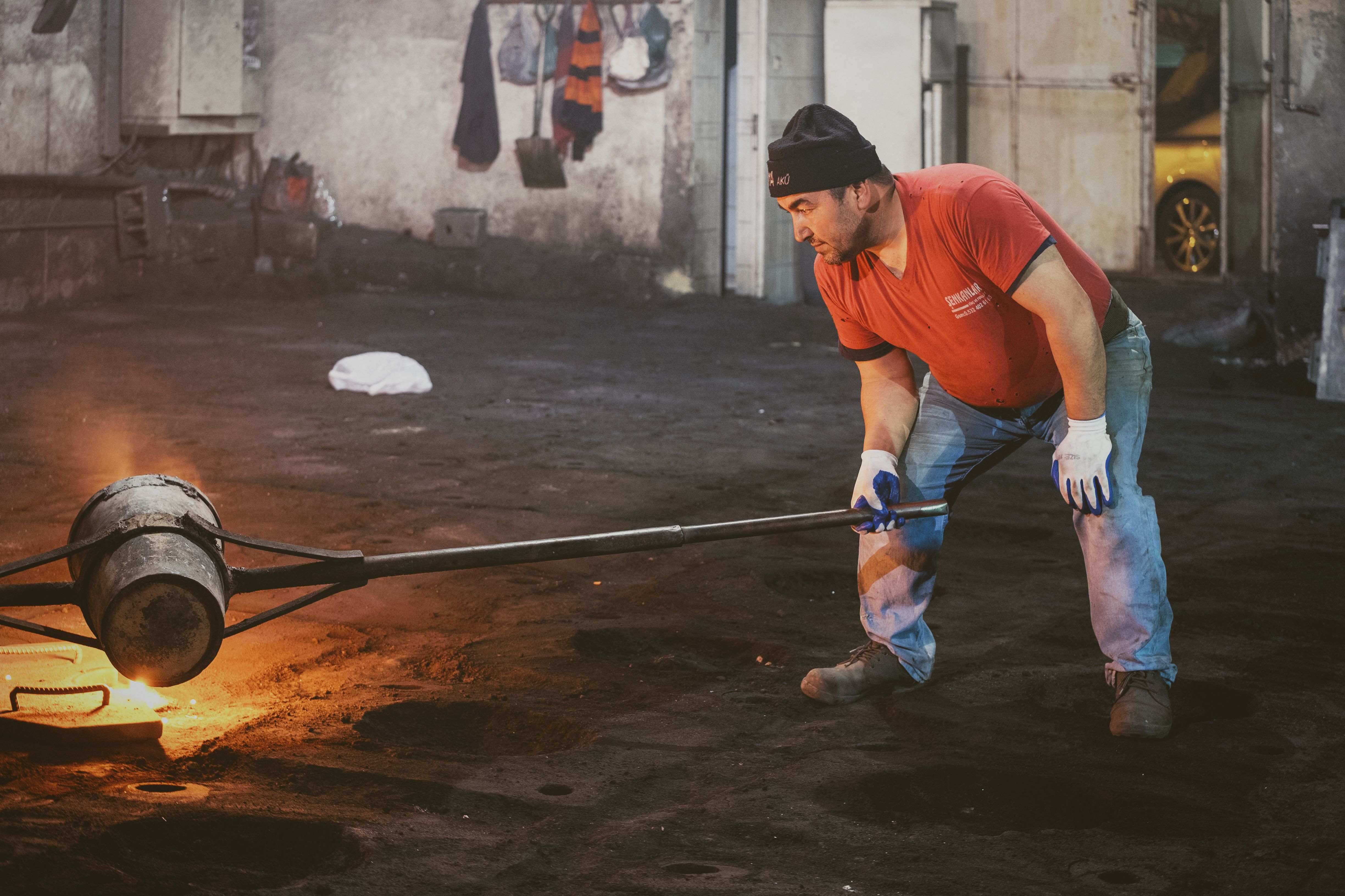 A dedicated worker managing molten material in a gritty industrial setting, showcasing hard work and focus.