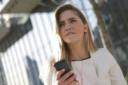 Mulher De Blazer Branco Segurando Um Smartphone Preto