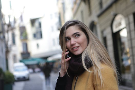 城市街道上，一位长发年轻女子微笑着在户外打电话