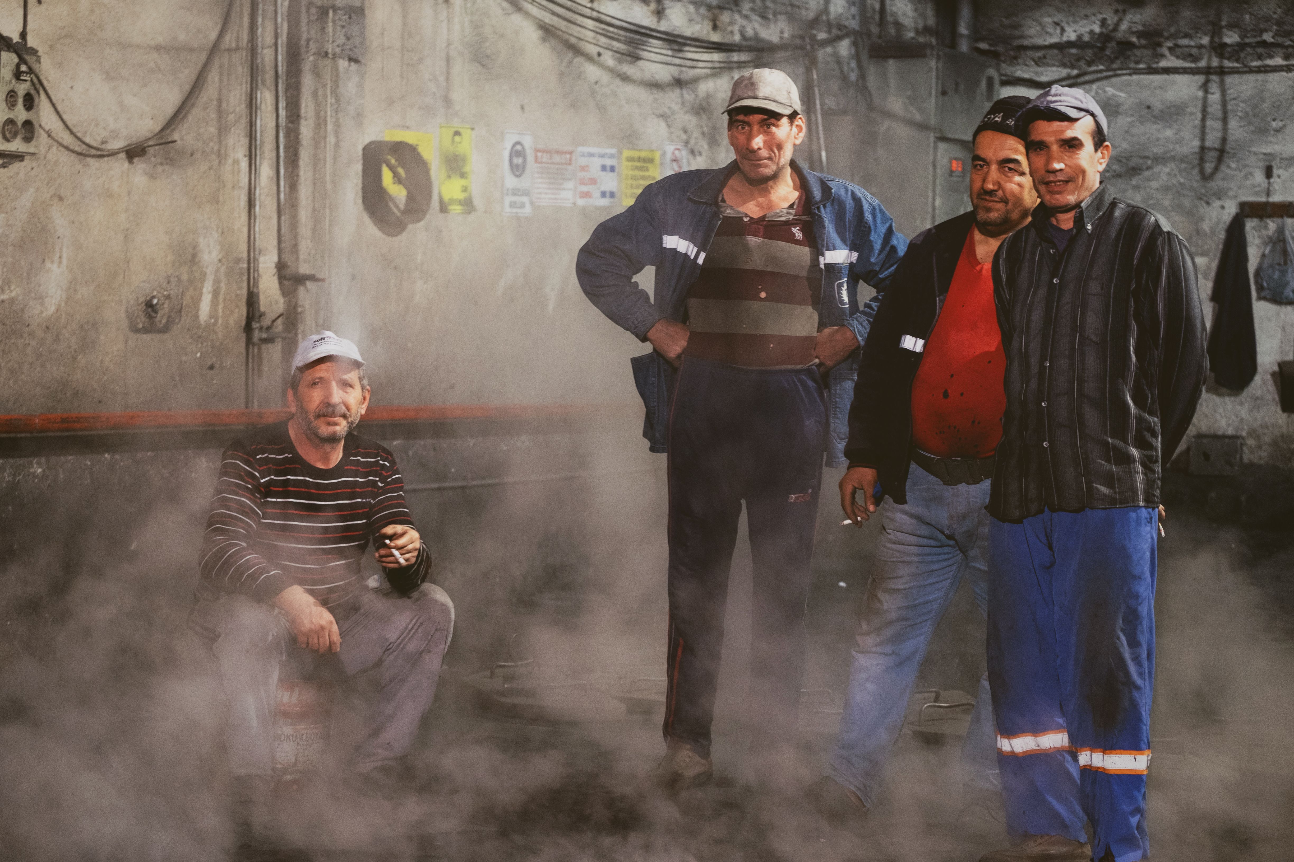 A group of industrial workers posing amidst machinery in a dimly lit factory setting.