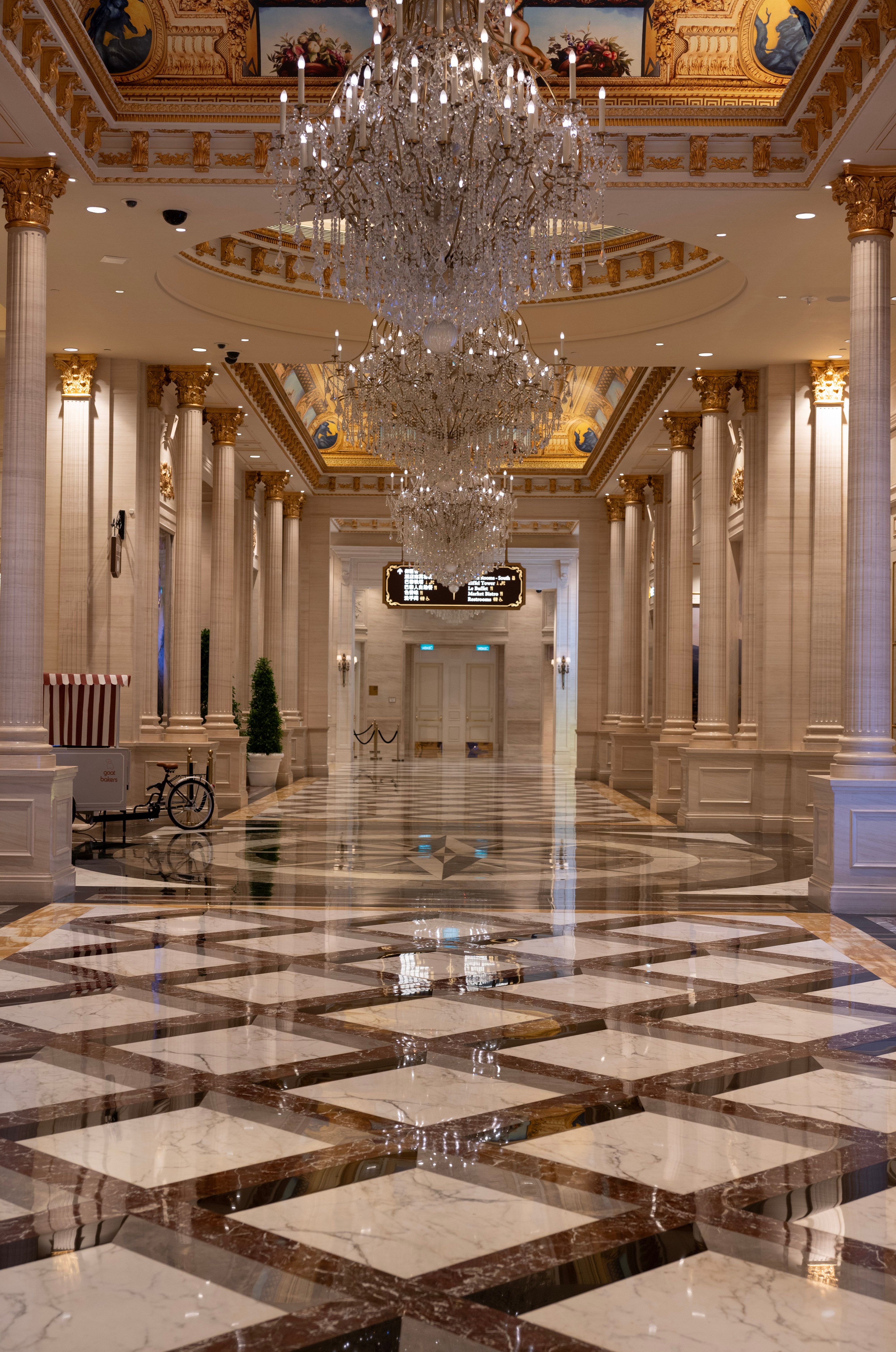 Elegant hall with chandeliers and marble flooring in a Macao casino resort, showcasing opulent interior design.