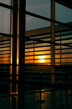 Contemporary building interior with dramatic sunset reflections on glass windows, showcasing geometric lines and warm tones.