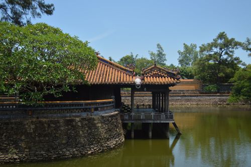 Free A serene view of a traditional Asian pavilion over a tranquil lake surrounded by lush greenery. Stock Photo