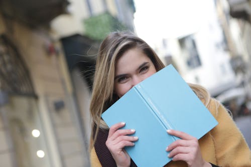 Женщина держит синюю книгу