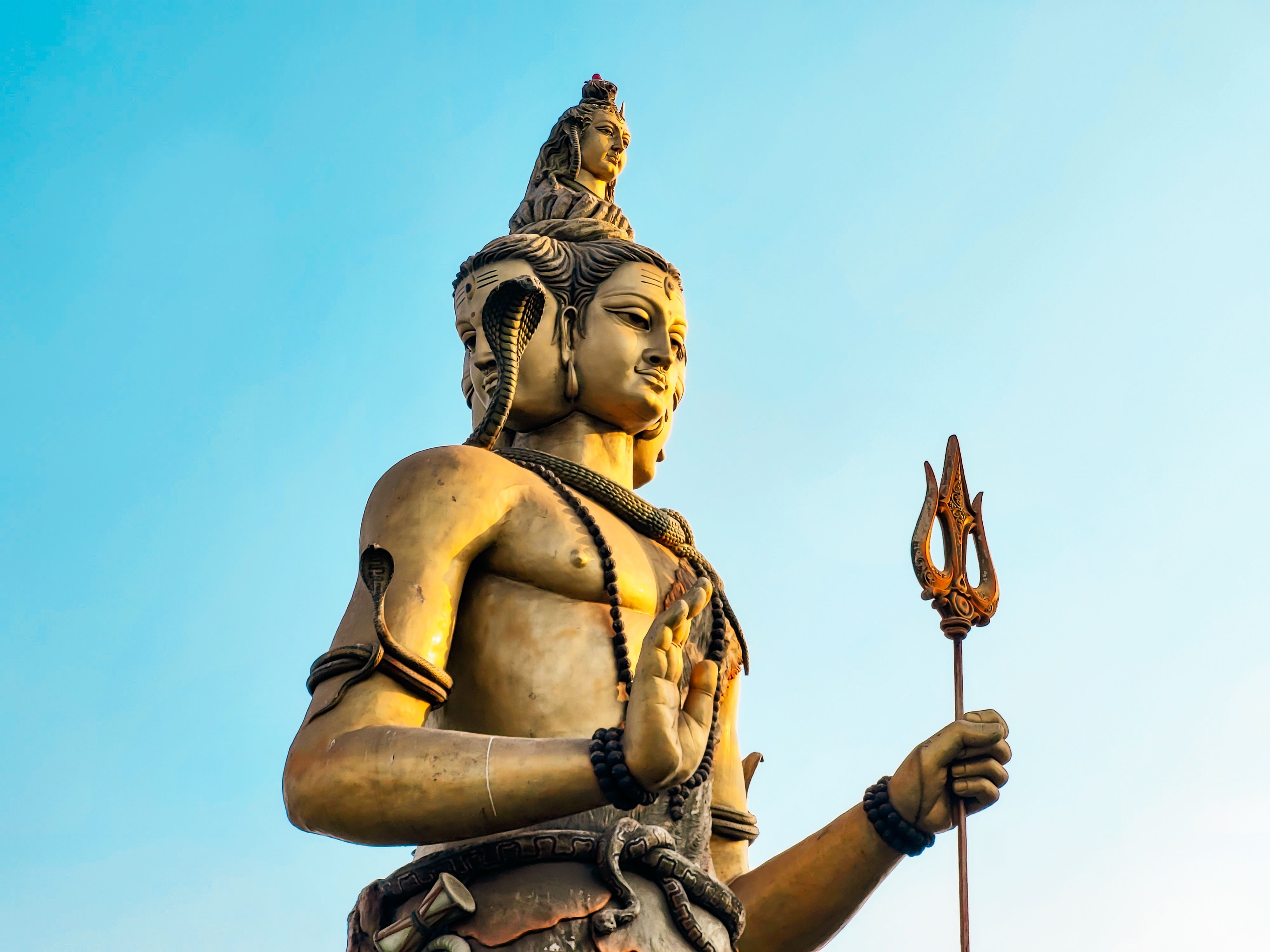 A stunning statue of Shiva with blue sky backdrop, showcasing intricate detail and cultural significance.