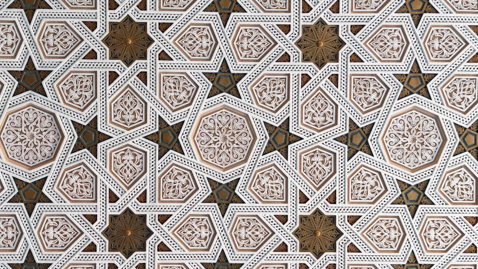 Detailed geometric pattern in Islamic tile art featuring intricate hexagonal motifs and star shapes.