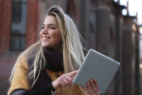Woman in Brown Coat Holding Silver Ipad