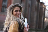 一位年轻女子在户外微笑着拿着平板电脑，展现休闲时尚风格