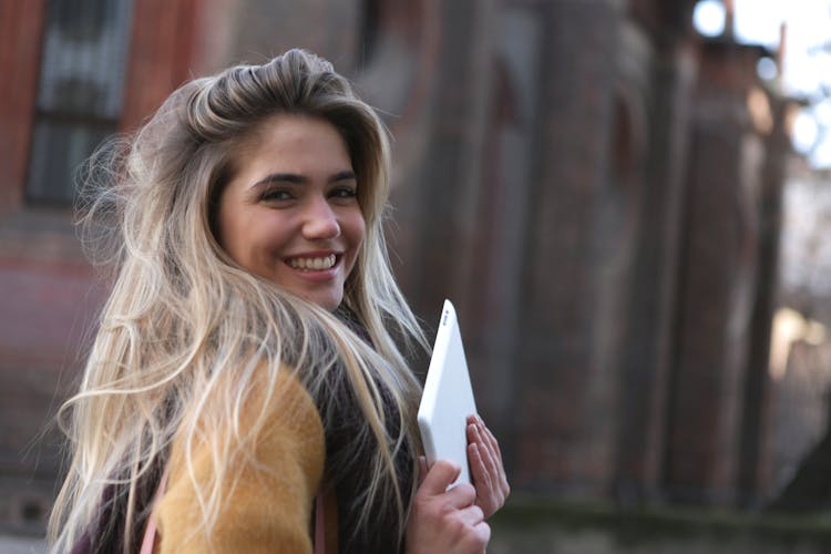 Woman In Brown Coat Holding A Silver Ipad