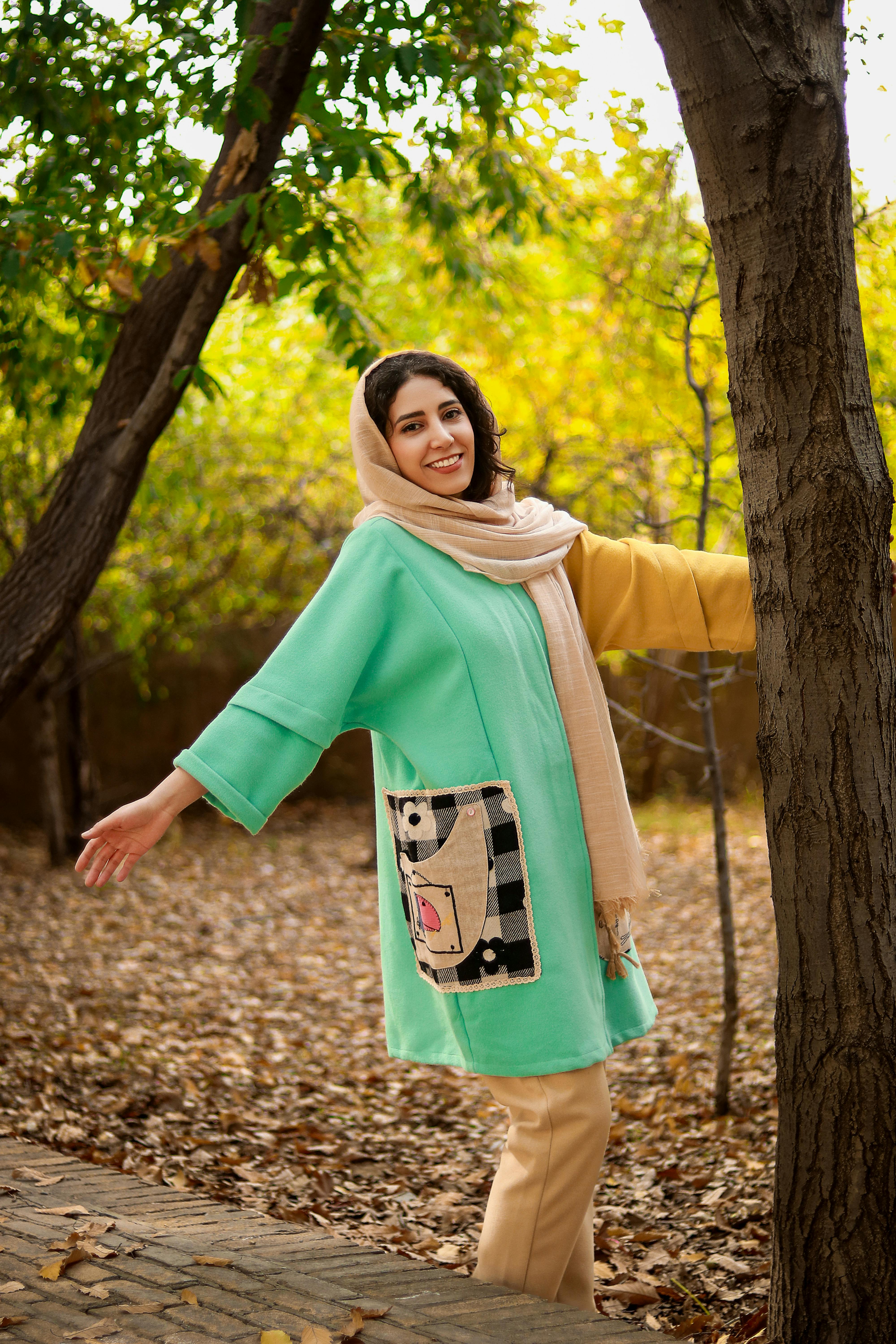 Joyful woman enjoying a sunny autumn day among trees in Tehran park.