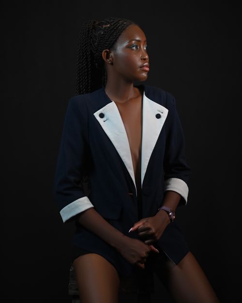 Free Confident woman poses in a stylish suit against a dark background, exuding elegance. Stock Photo
