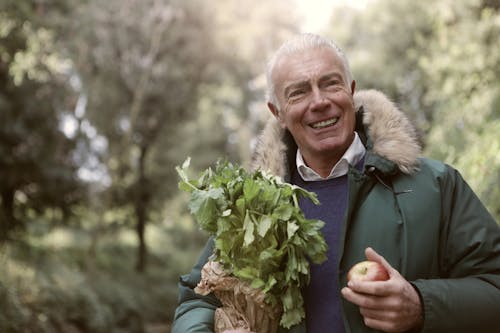 Man In Green Jacket Holding Green Plant