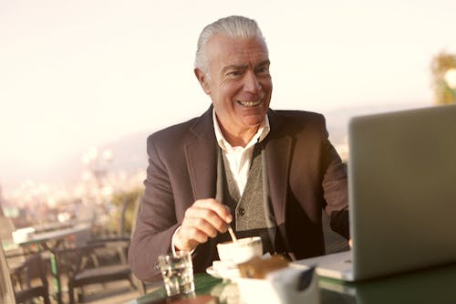 Man in Black Suit Looking at Laptop