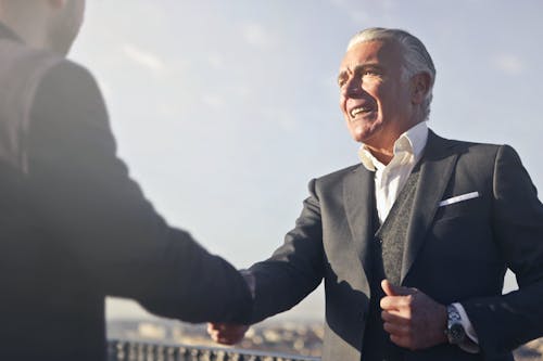 Free Man in Black Suit Shaking Hands with Another Man Stock Photo