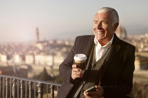 Man In Black Suit Holding A Coffee Cup