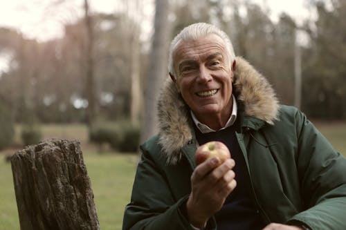 무료 사과 들고 녹색 재킷에 웃는 남자 스톡 사진