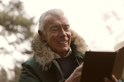 Man In Green Jacket Smiling While Reading