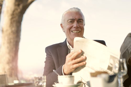 Free Man In Black Suit Holding A Newspaper Stock Photo