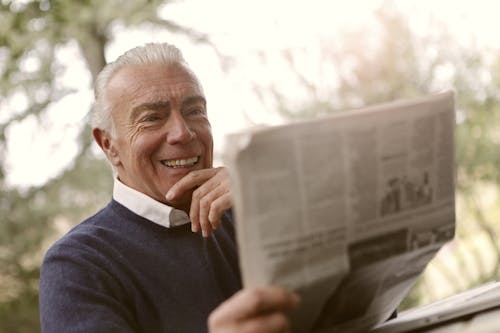 Free Man In Navy Blue Sweater Holding Newspaper Stock Photo