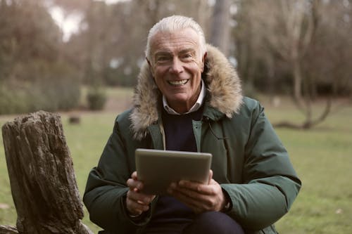 Free Adult Man Wearing Green Jacket Holding a Tablet Stock Photo