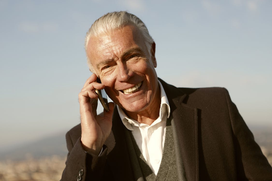 Free Man in Black Suit Using A Cellphone Stock Photo