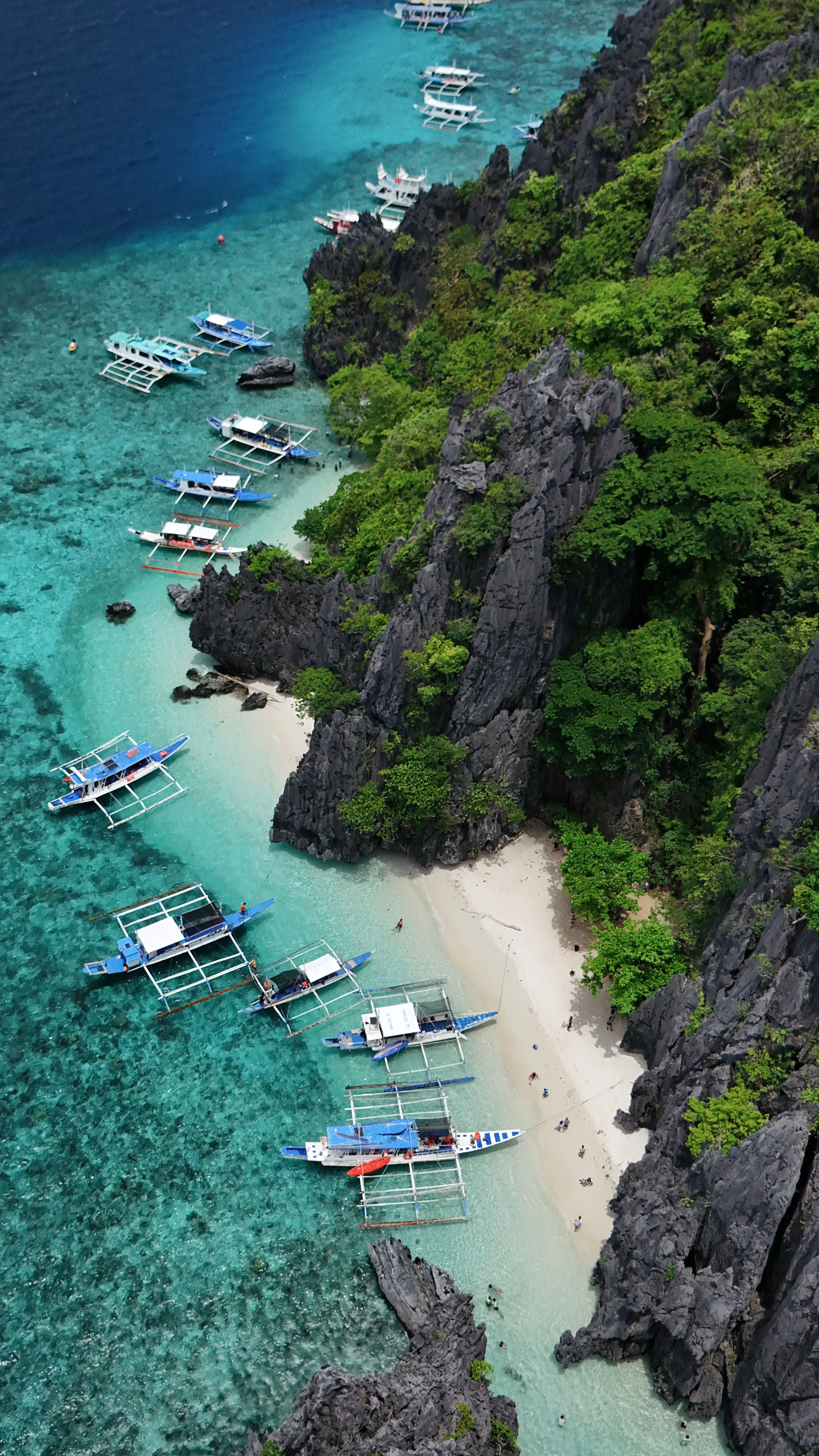 Aerial view of limestone cliffs and a turquoise lagoon with boats in Palawan, Philippines