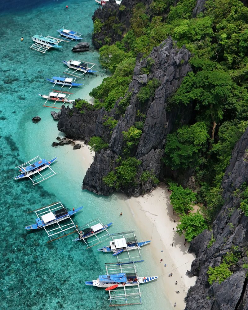 Aerial view of limestone cliffs and a turquoise lagoon with boats in Palawan, Philippines