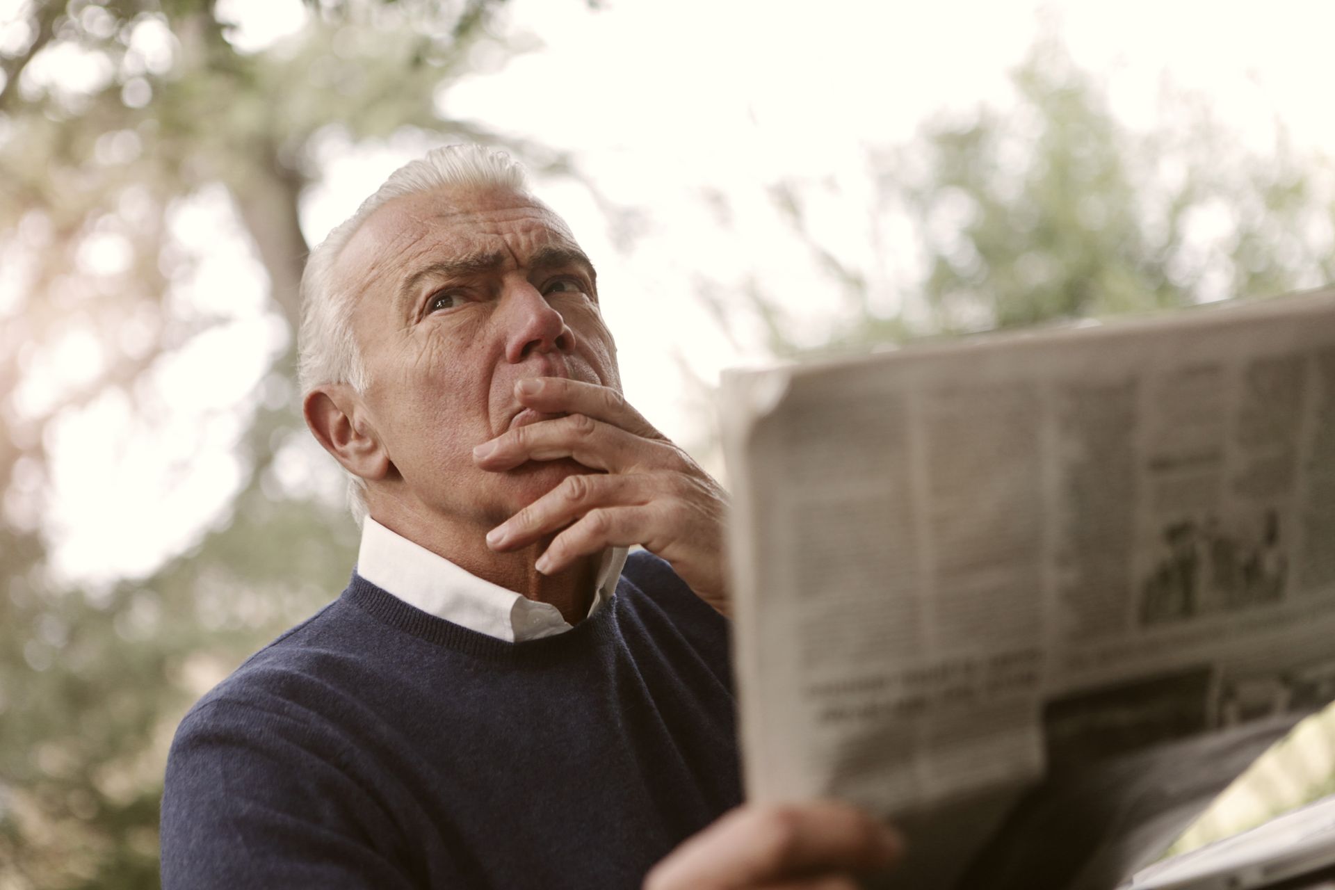 Man in Blue Sweater Reading a Newspaper