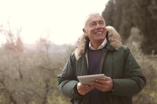 Man In Green Jacket Holding A Gadget