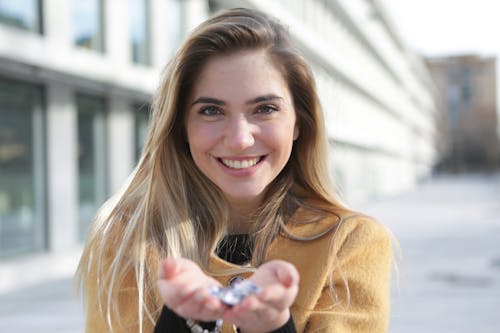Free Smiling Woman in Brown Sweater Holding Silver Ring Stock Photo