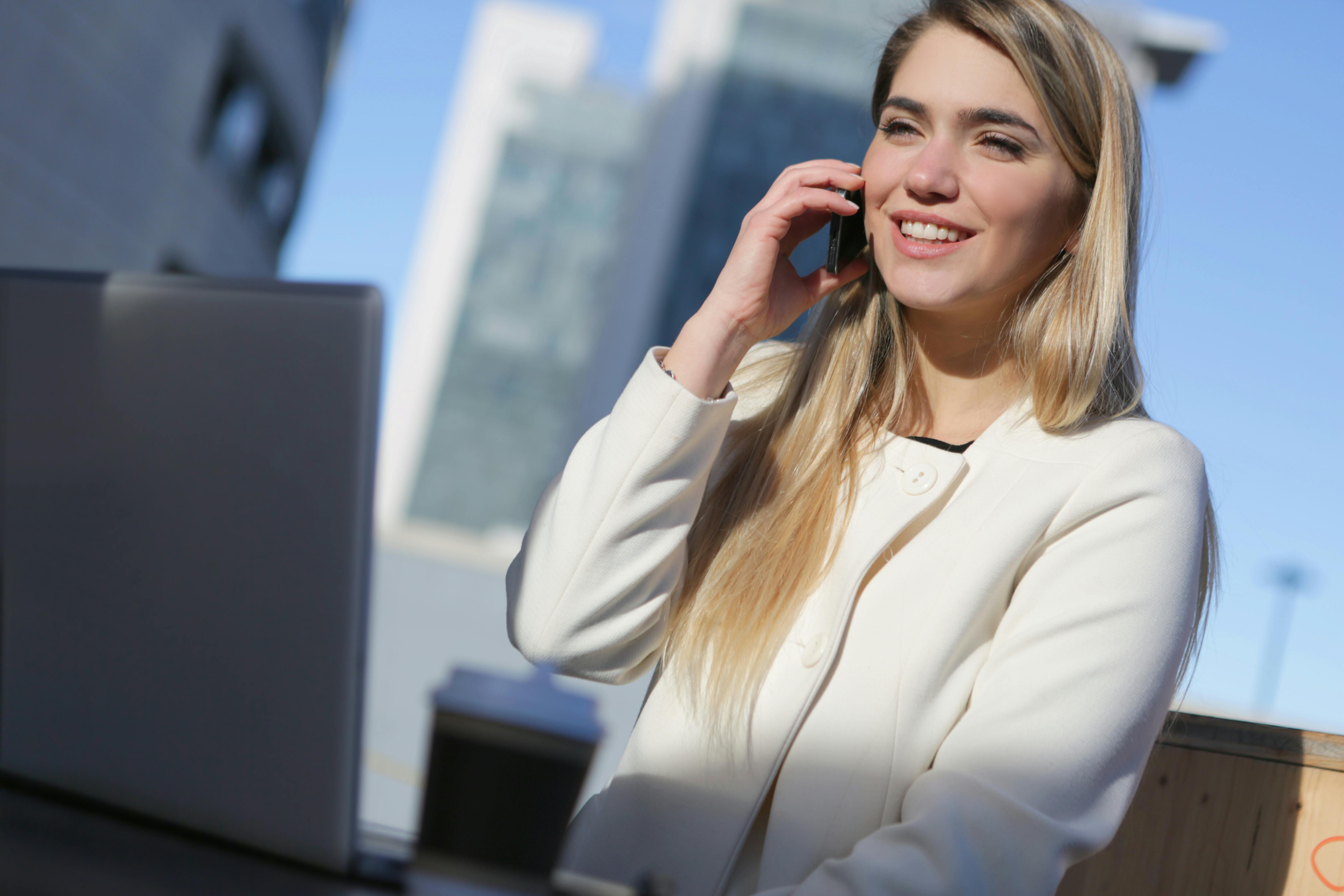 woman in white long sleeve shirt holding black smartphone