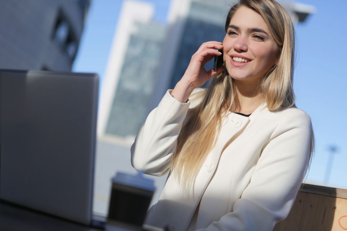 Free Woman in White Long Sleeve Shirt Holding Black Smartphone Stock Photo